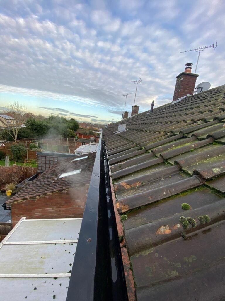 Freshly cleared gutter along a tiled roof after gutter cleaning