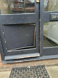 Damaged communal entrance door panel before repair